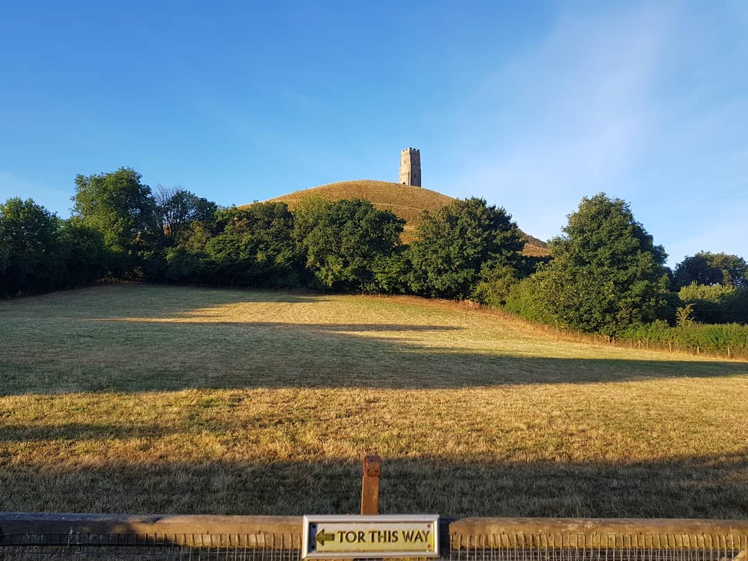 Tor in Glastonbury against a sign that says Tor This Way